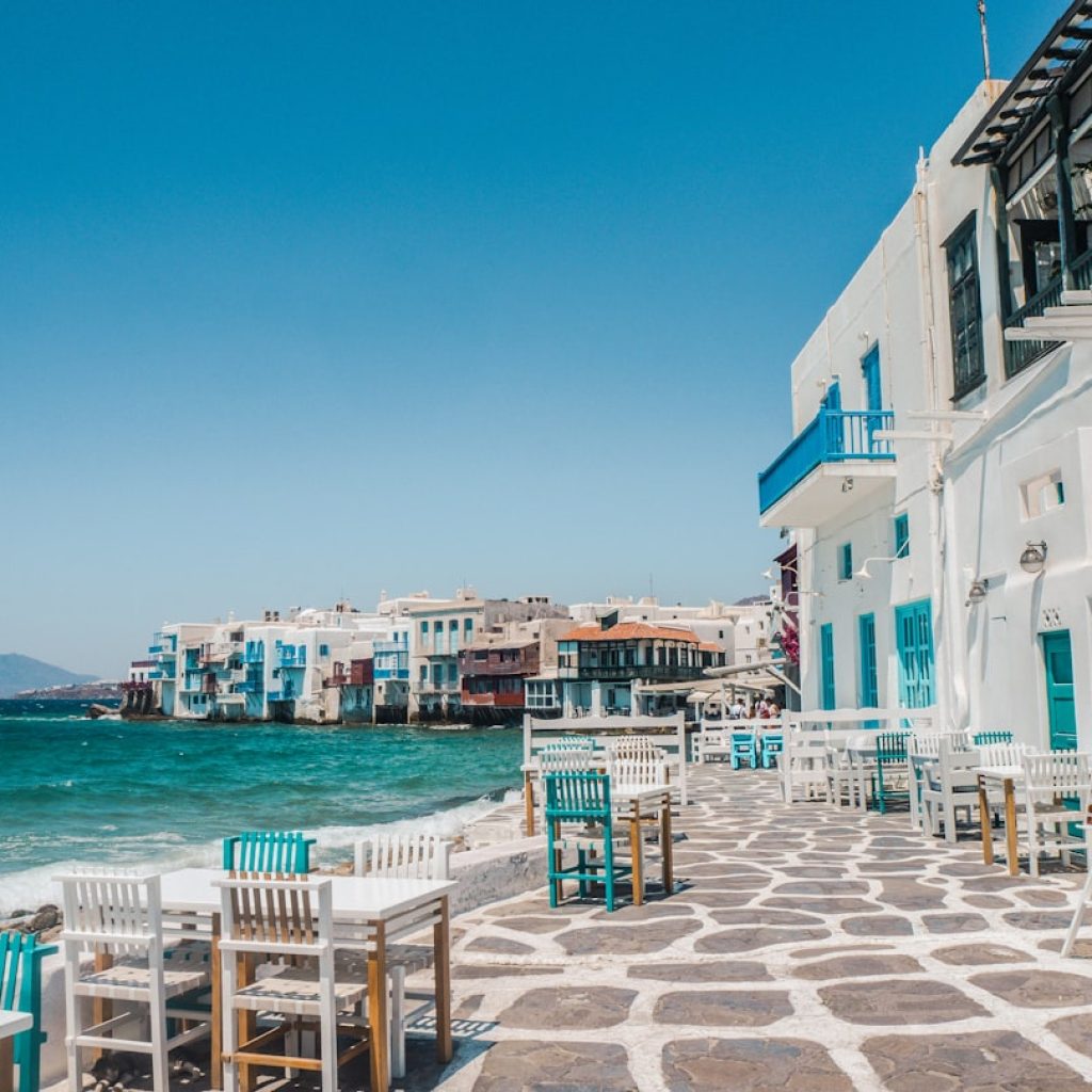 Little Venice neighborhood in Mykonos, Greece, with whitewashed buildings and outdoor cafe tables along the waterfront